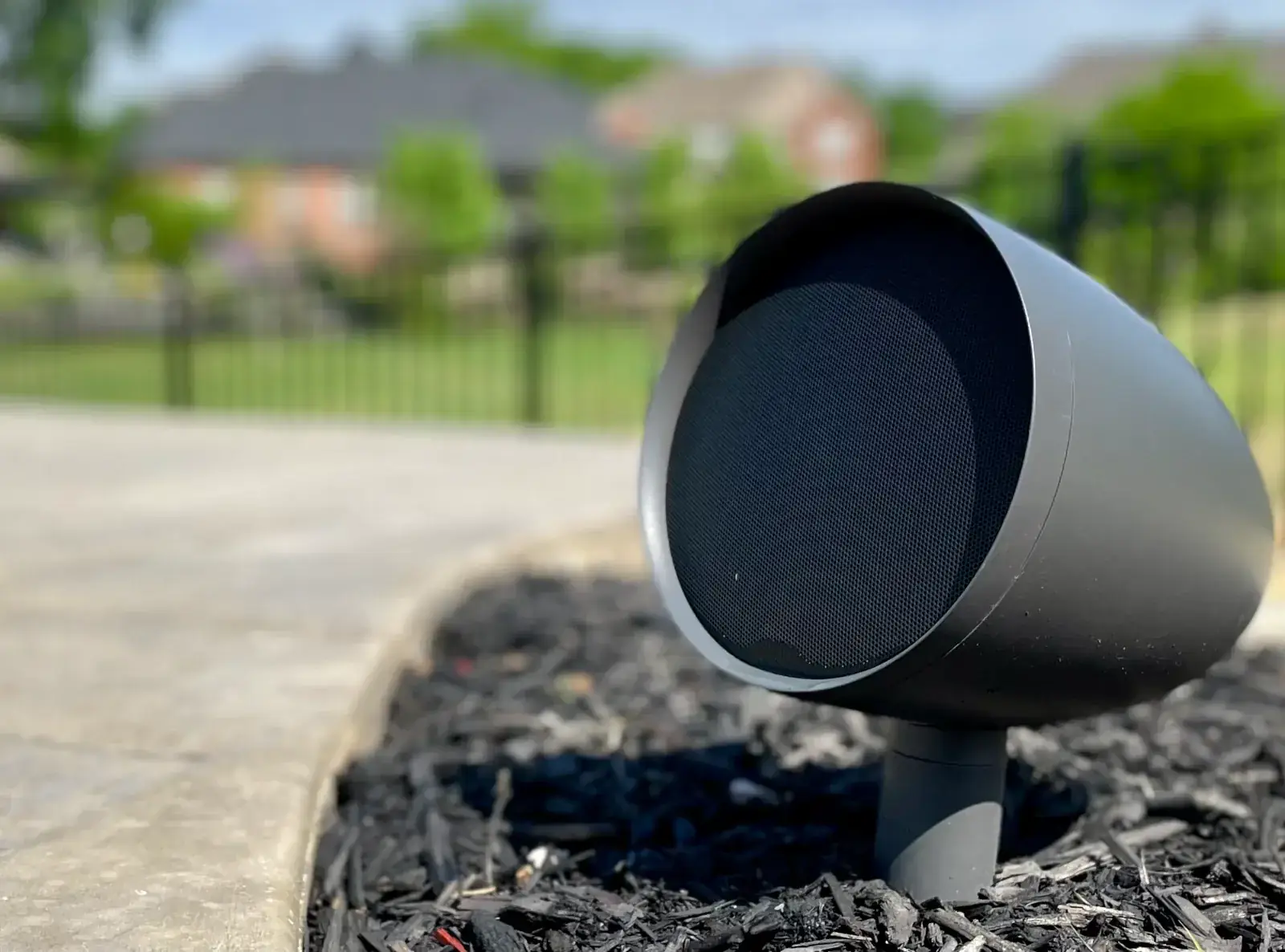 An Origin Acoustics outdoor landscape speaker installed in a mulch bed beside a driveway in Middle Tennessee by Light TN