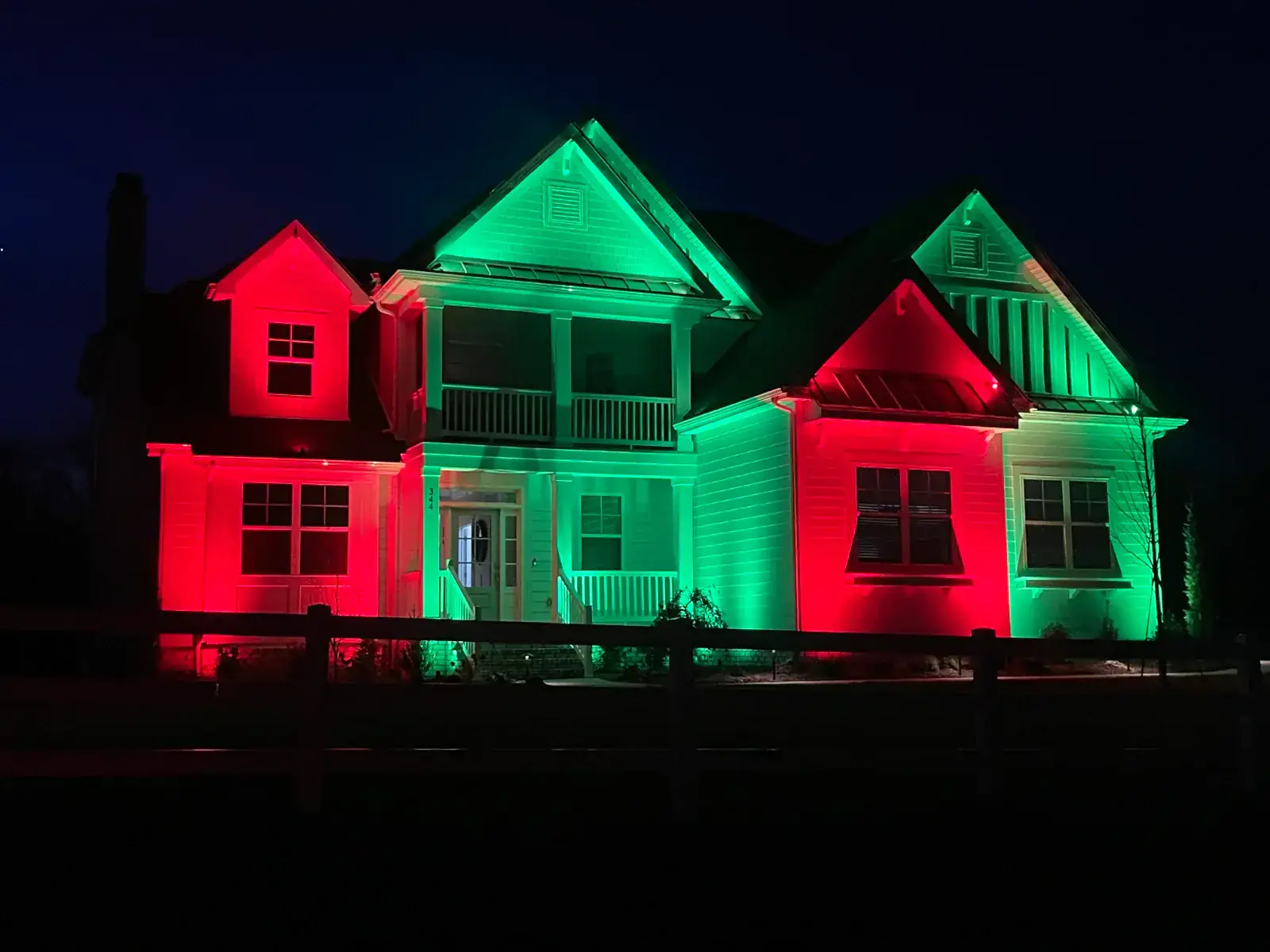 Smart lighting systems showing programmable color control on a Middle Tennessee home lit in red and green at night by Light TN