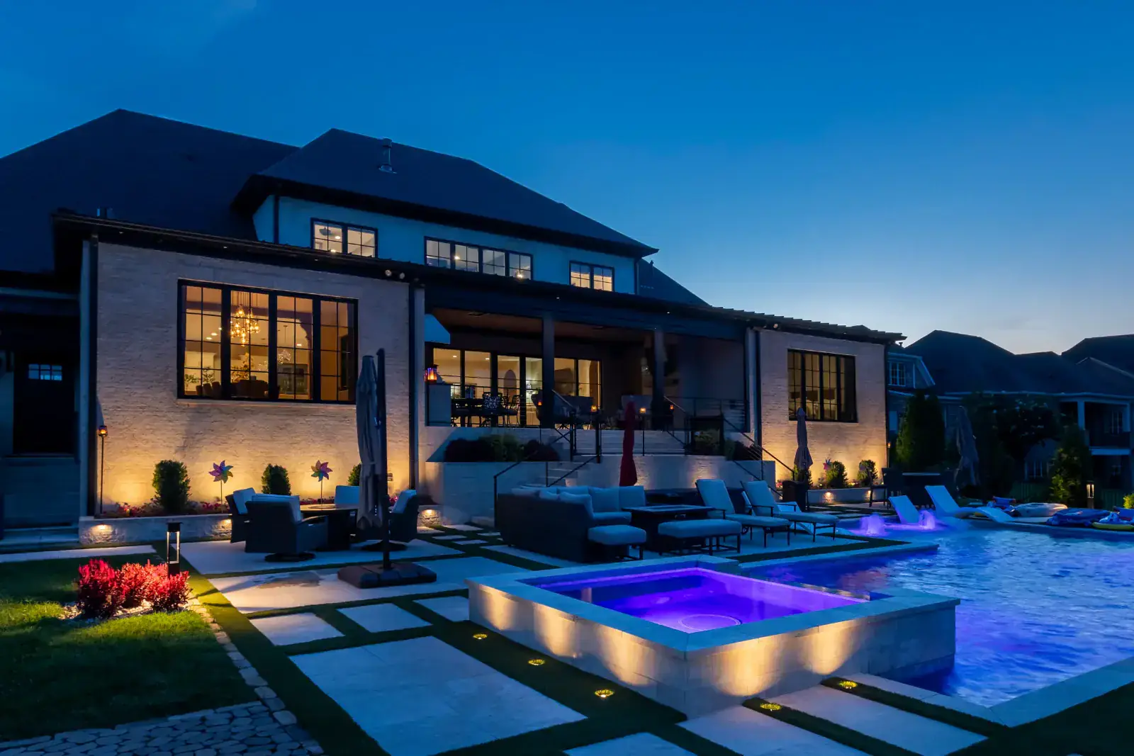 A Middle Tennessee estate at night with architectural uplighting, illuminated spa, and pool area designed by Light TN